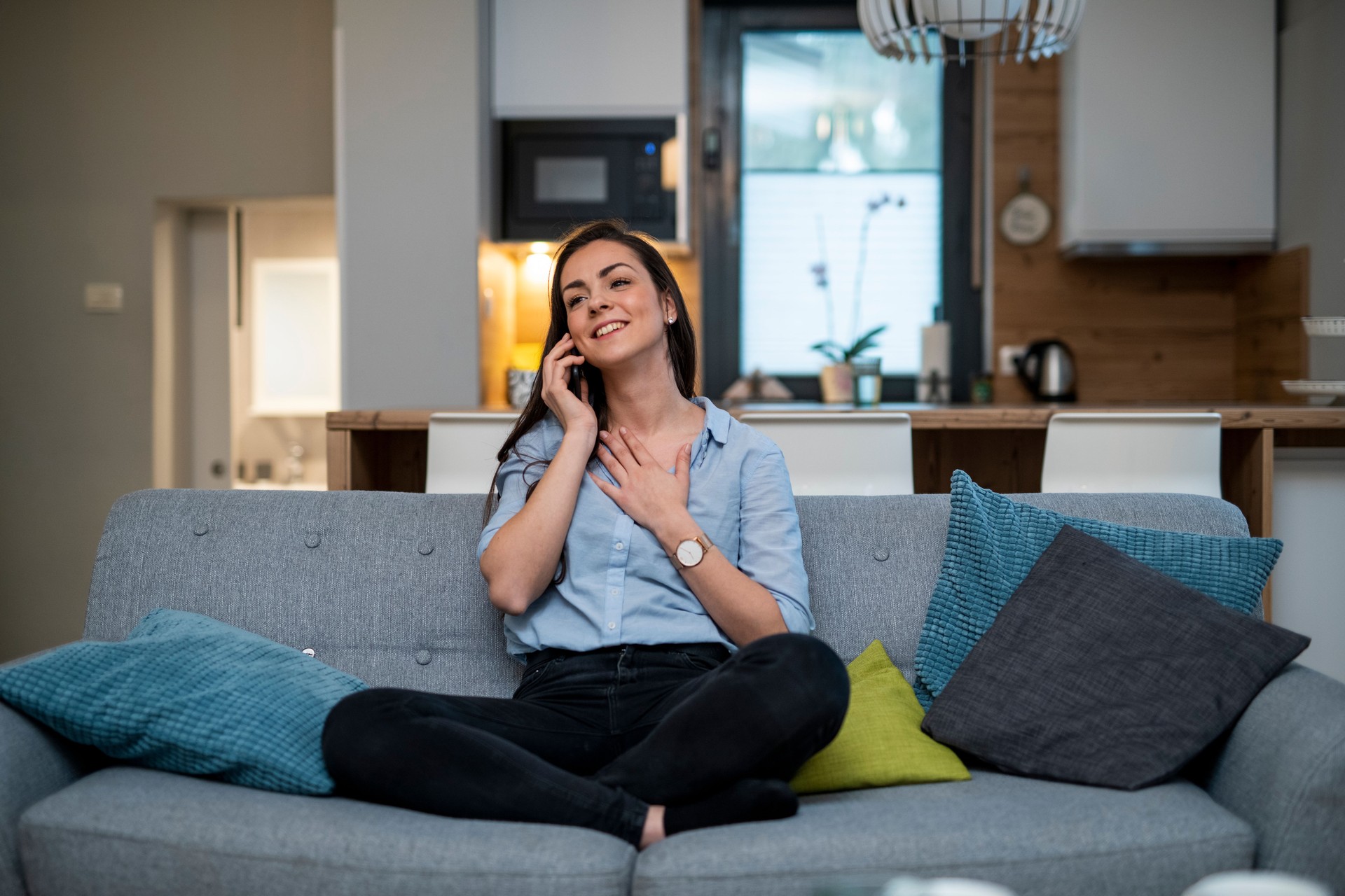 Young woman sitting on the couch and using smart phone
